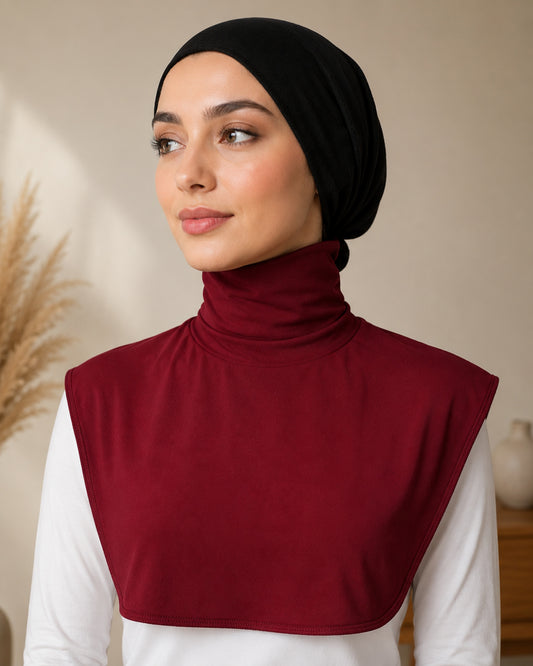 Woman wearing a black hijab and maroon neck cover against a neutral background

