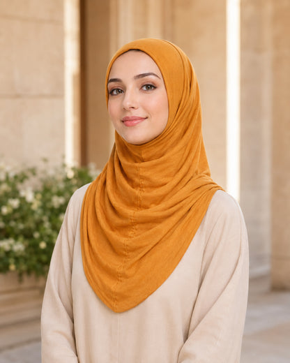 Woman wearing a mustard hijab in an indoor setting with neutral background

