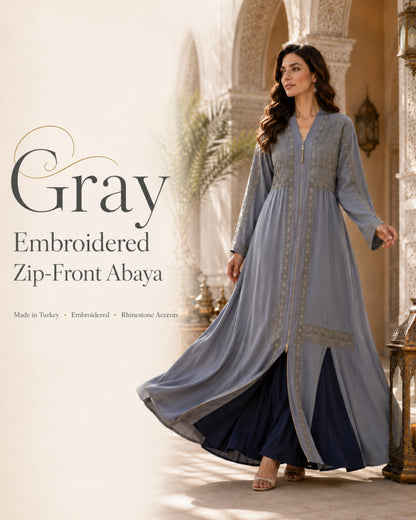 Woman wearing a gray embroidered zip-front abaya in an elegant setting.

