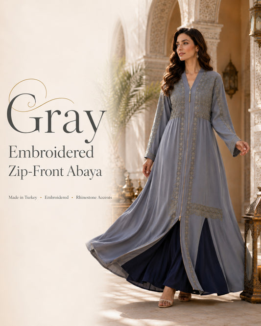 Woman wearing a gray embroidered zip-front abaya in an elegant setting.

