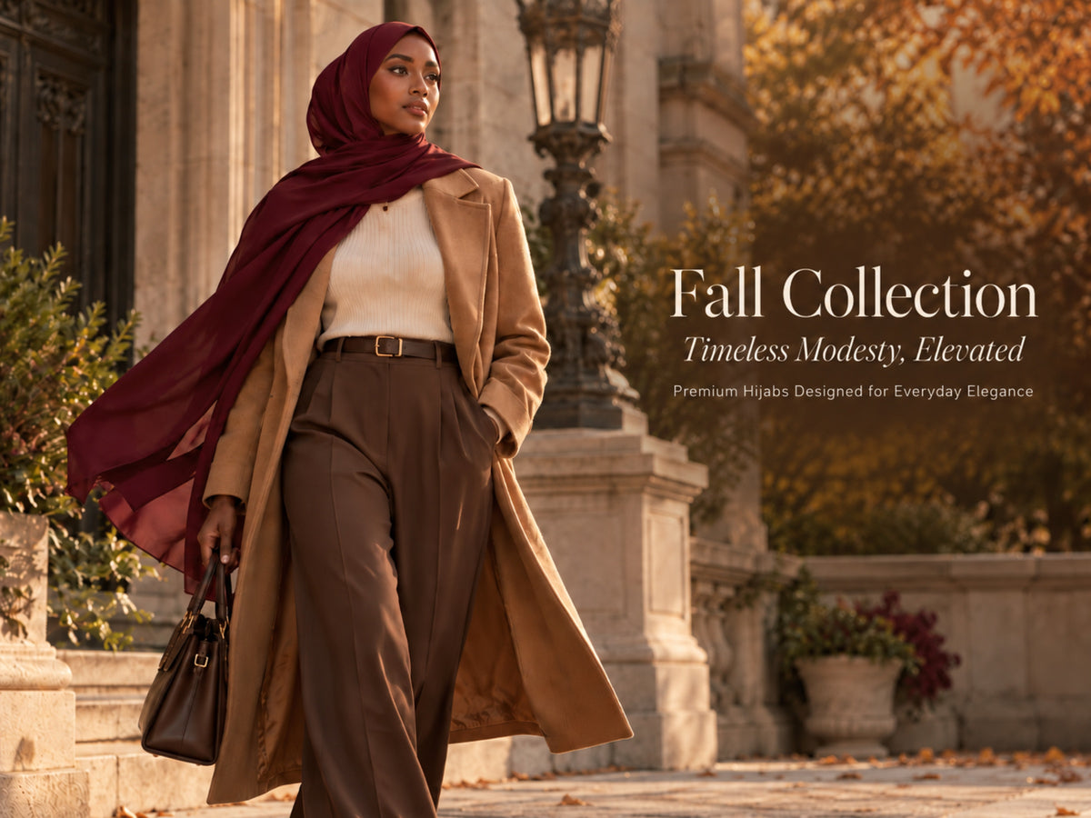 Woman in a deep burgundy hijab and camel coat walking through an elegant autumn setting in warm golden light.