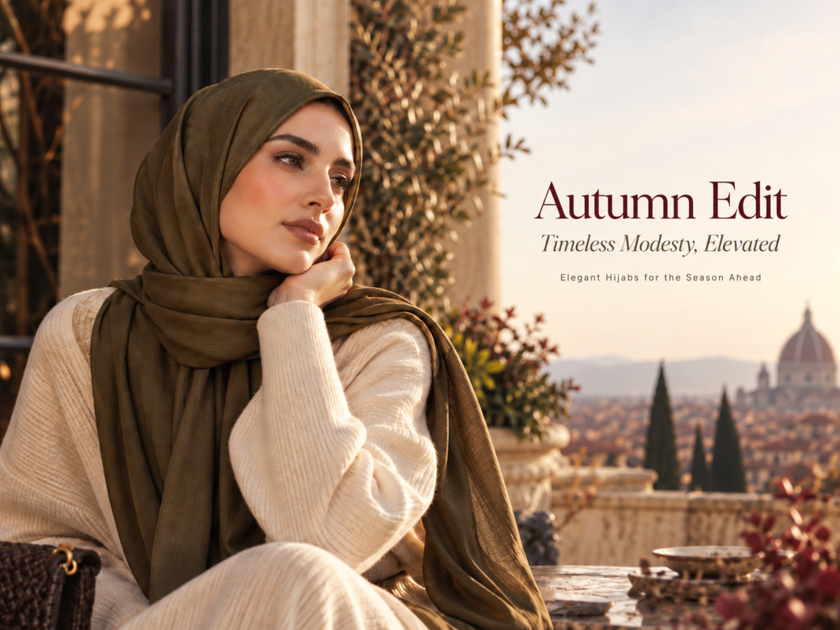 Woman in an olive green hijab and cream knitwear seated on a terrace overlooking a softly lit autumn cityscape.